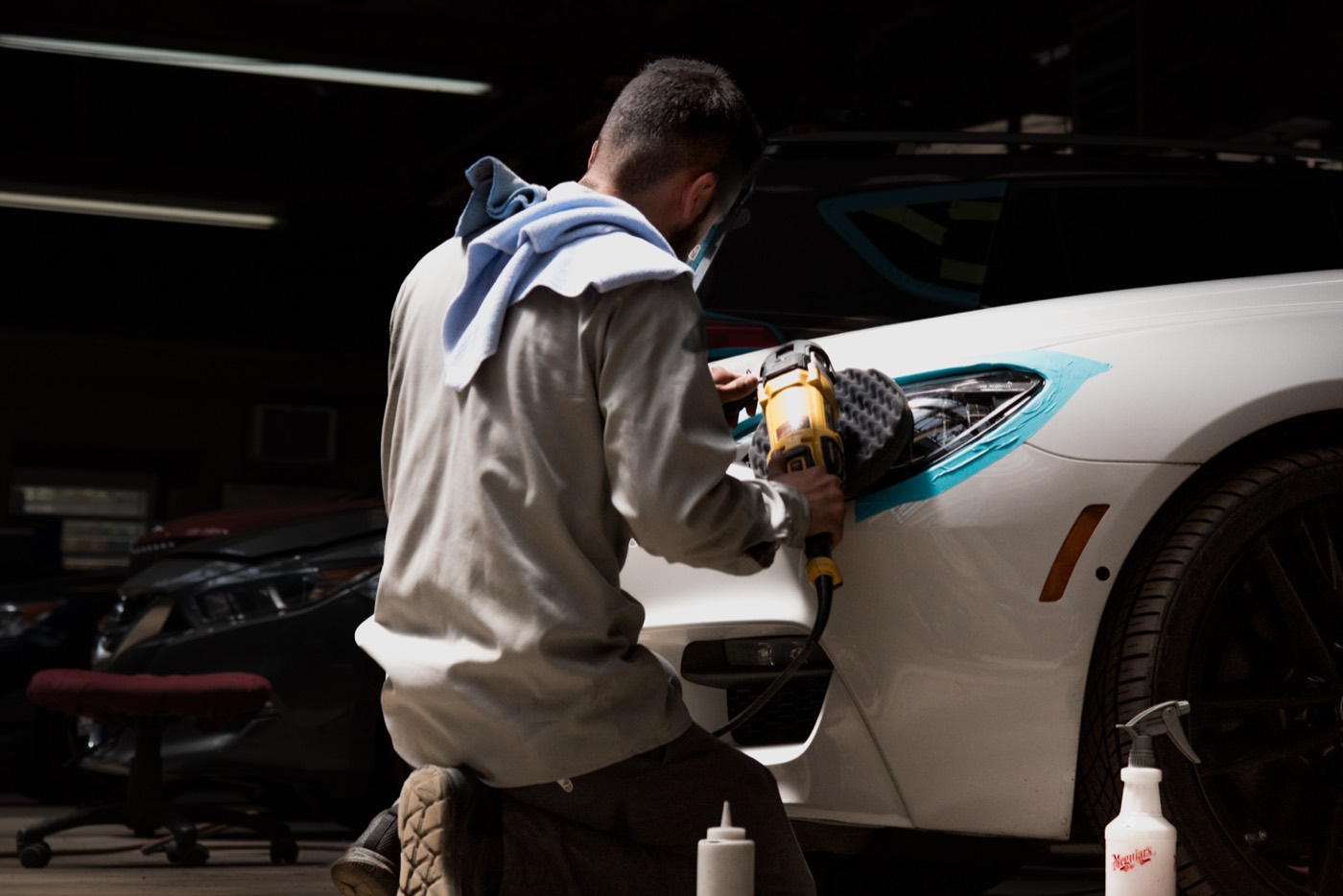 Technician polishing the front of a white car