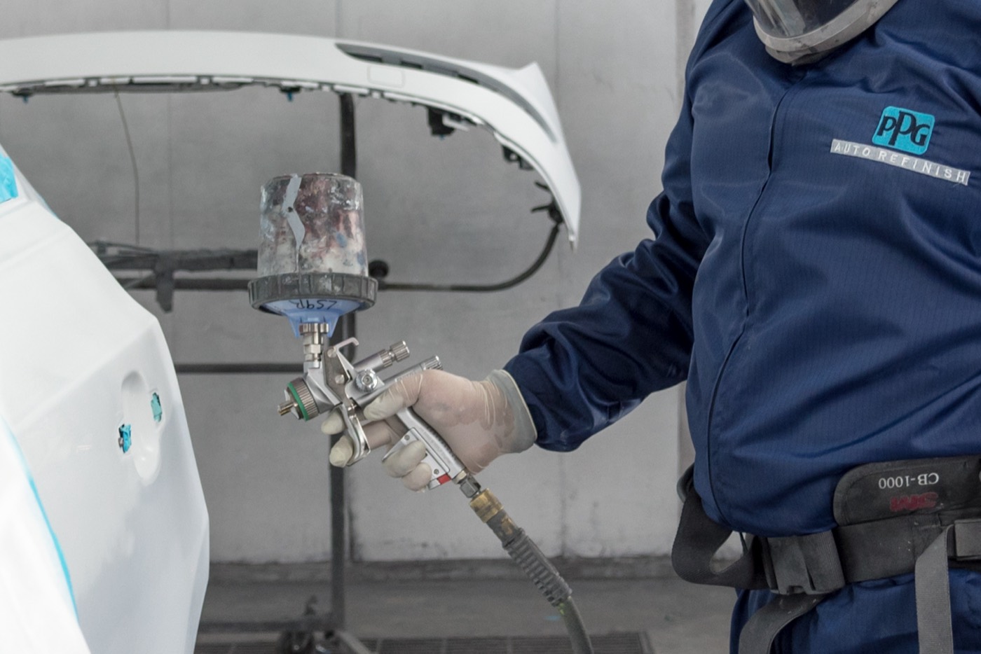 Painter in PPG gear spraying a bumper in the booth